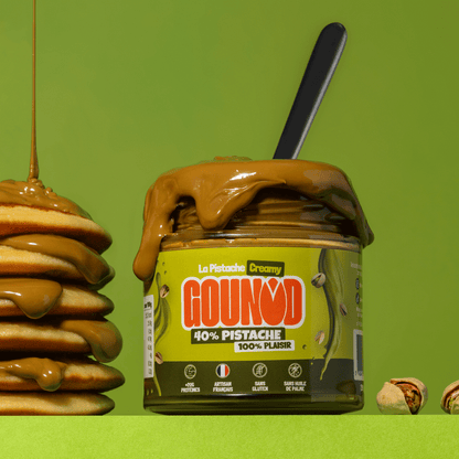 Pot de pâte à tartiner pistache Gounod Creamy posé à côté d'une pile de pancakes avec de la pâte qui coule.